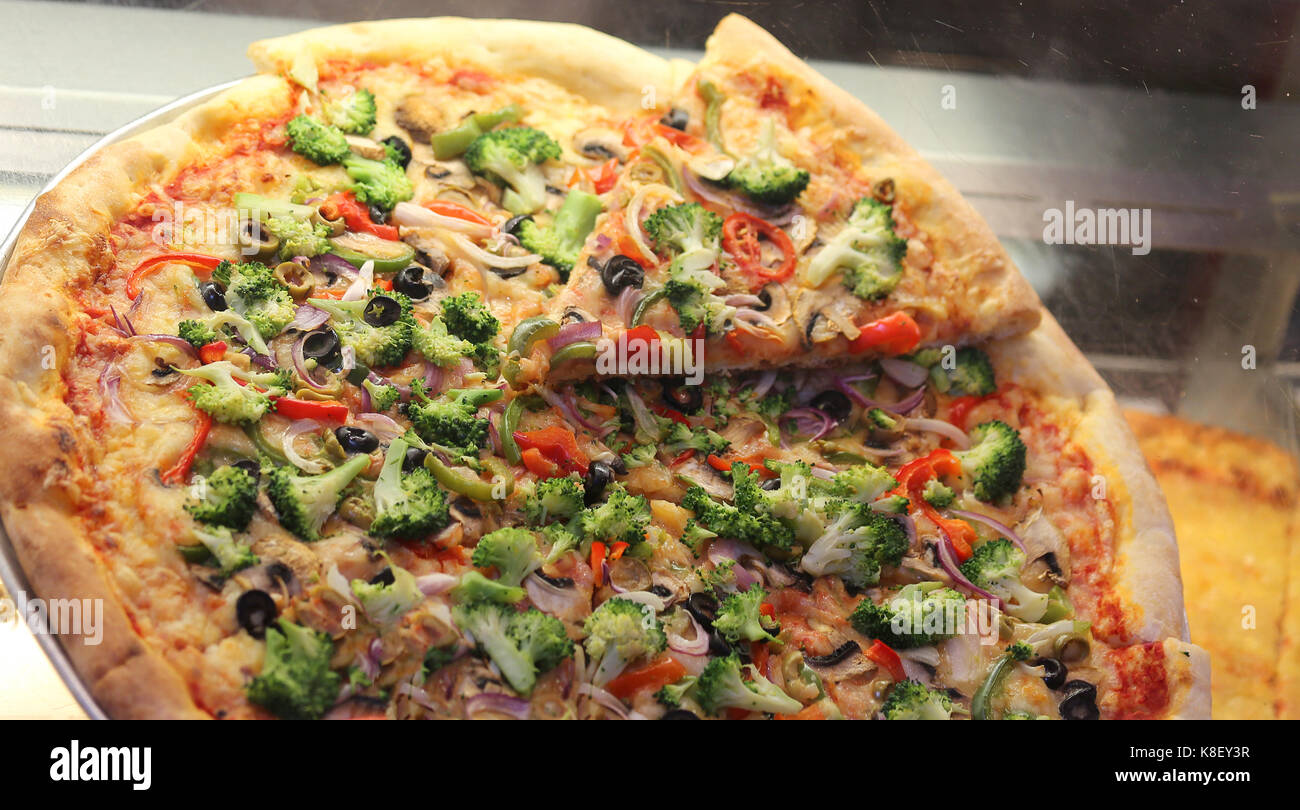 Pizza ripiena con pomodoro e mozzarella e broccoli sulla vendita a fette Foto Stock