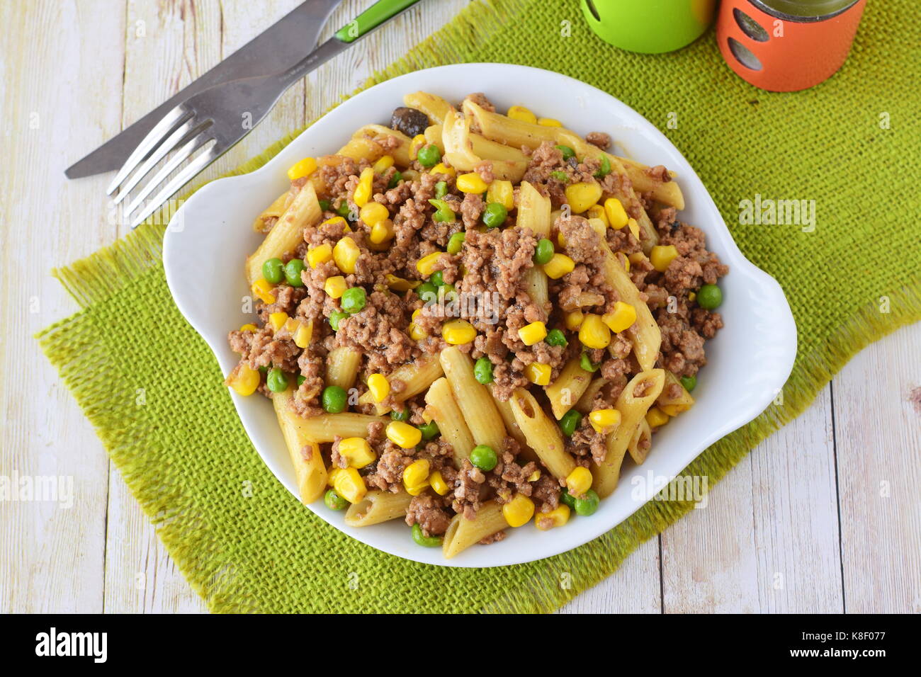 Pasta con carne tritata, i piselli e il mais giallo in una piastra bianca. cucina casalinga. Il mangiare sano concetto Foto Stock