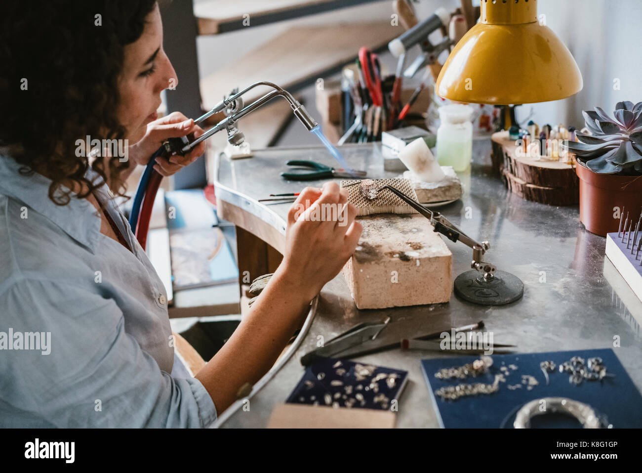 Il gioielliere femmina con torcia soffiante al banco di lavoro Foto Stock
