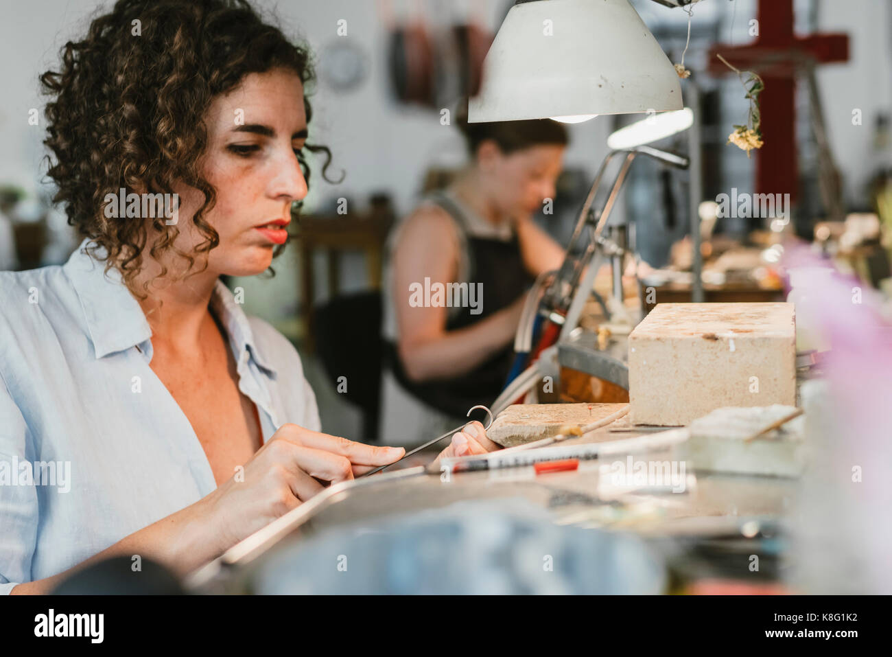 Il gioielliere della femmina di formatura di metallo argento al banco di lavoro Foto Stock