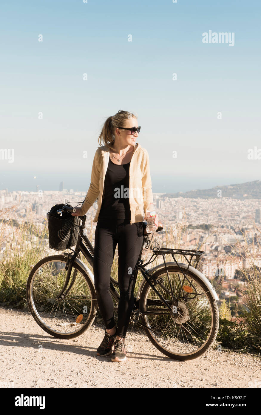 Donna gita in bicicletta, città in background, Barcellona, in Catalogna, Spagna Foto Stock