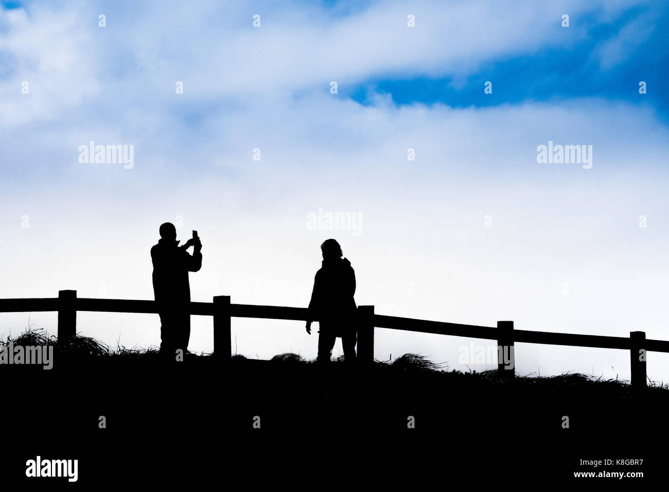 La silhouette di un uomo con il suo smartphone per fotografare il suo partner. Foto Stock