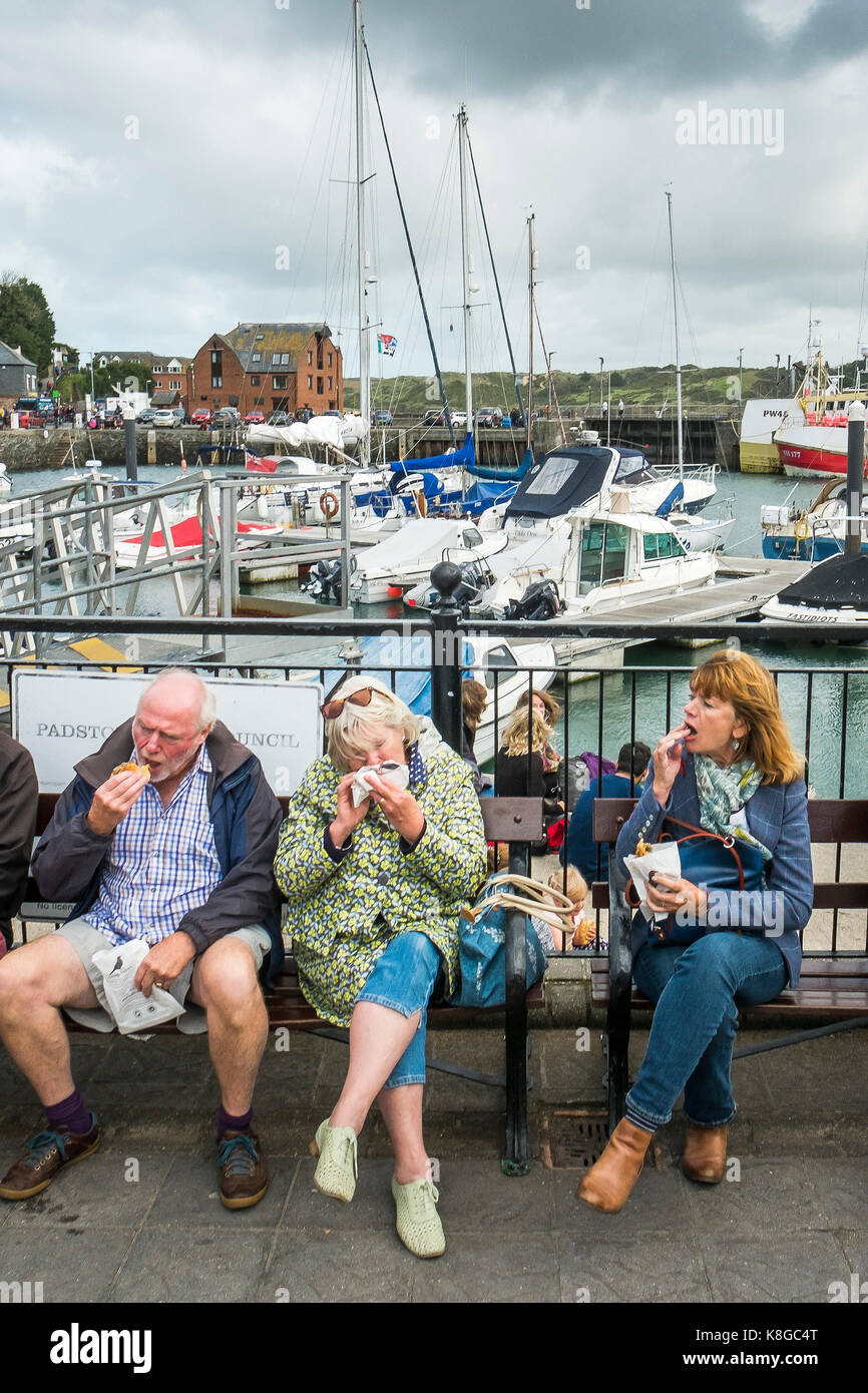 Padstow - turisti seduta su una panchina a mangiare pasties vicino a Padstow porto sulla North Cornwall coast. Foto Stock