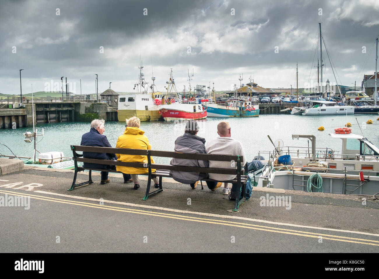 Padstow - la gente seduta su una panchina sul molo che si affaccia sul porto di padstow sulla North Cornwall coast. Foto Stock