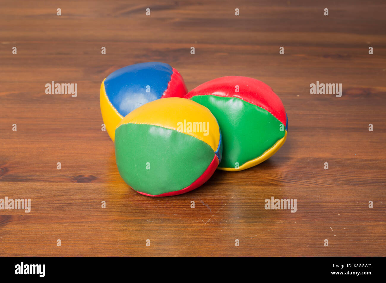 Tre colorate sfere di giocoleria in un triangolo su una tavola di legno Foto Stock