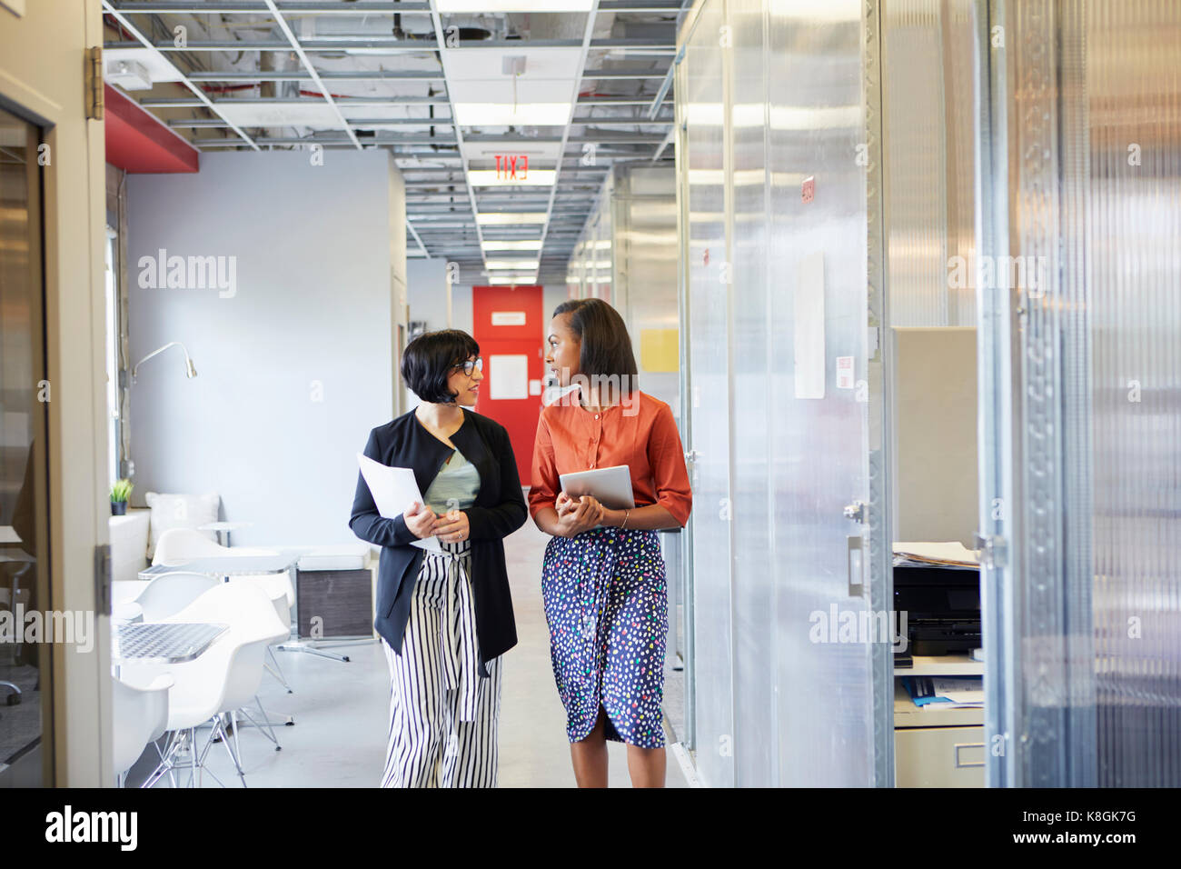 Due imprenditrici a camminare lungo il corridoio di ufficio, in conversazione Foto Stock