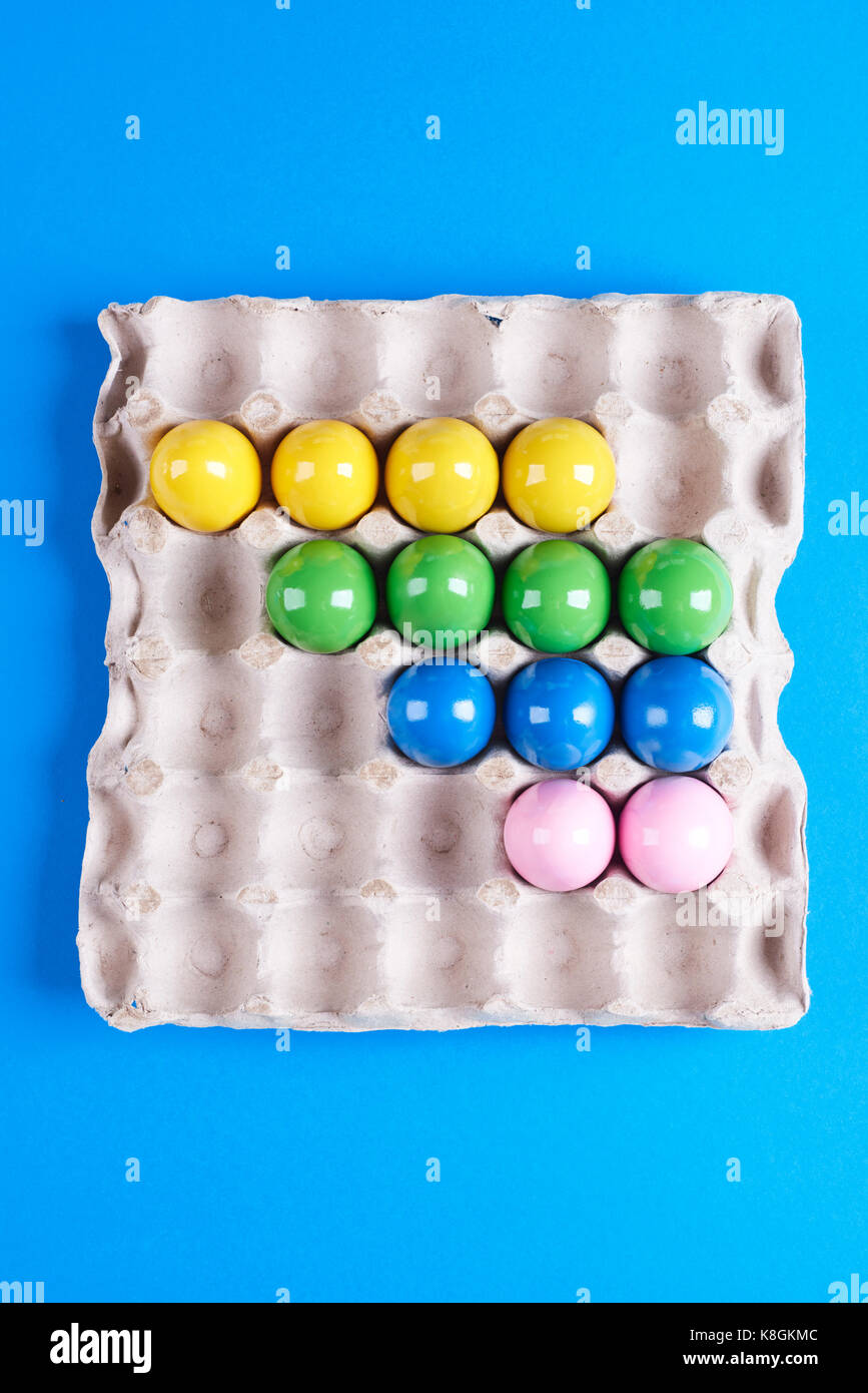 Vista aerea del multi- verniciato colorato le uova nel vassoio su sfondo blu Foto Stock