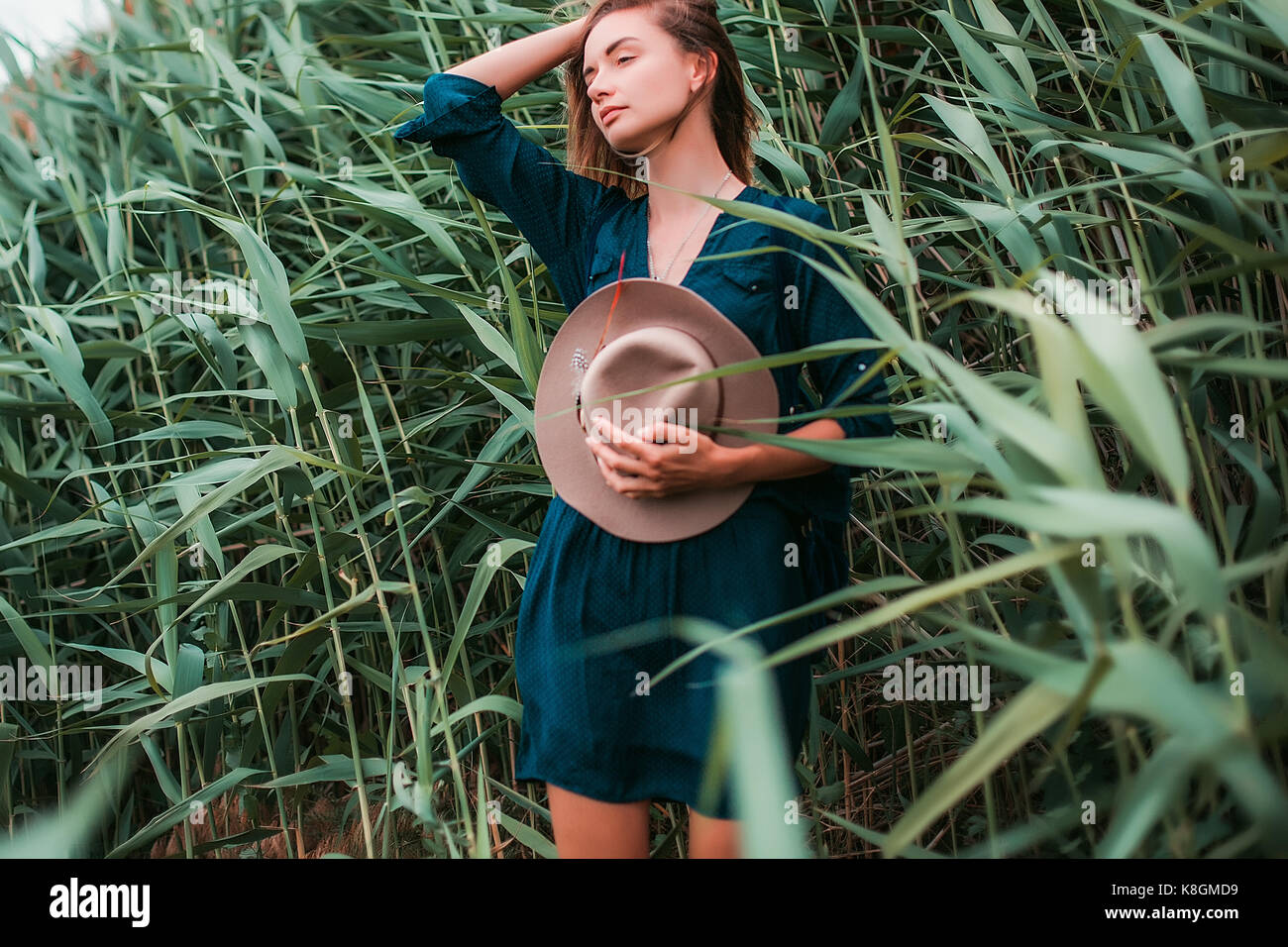 Metà donna adulta accanto a erba lunga, toccando i capelli e respirare aria fresca Foto Stock