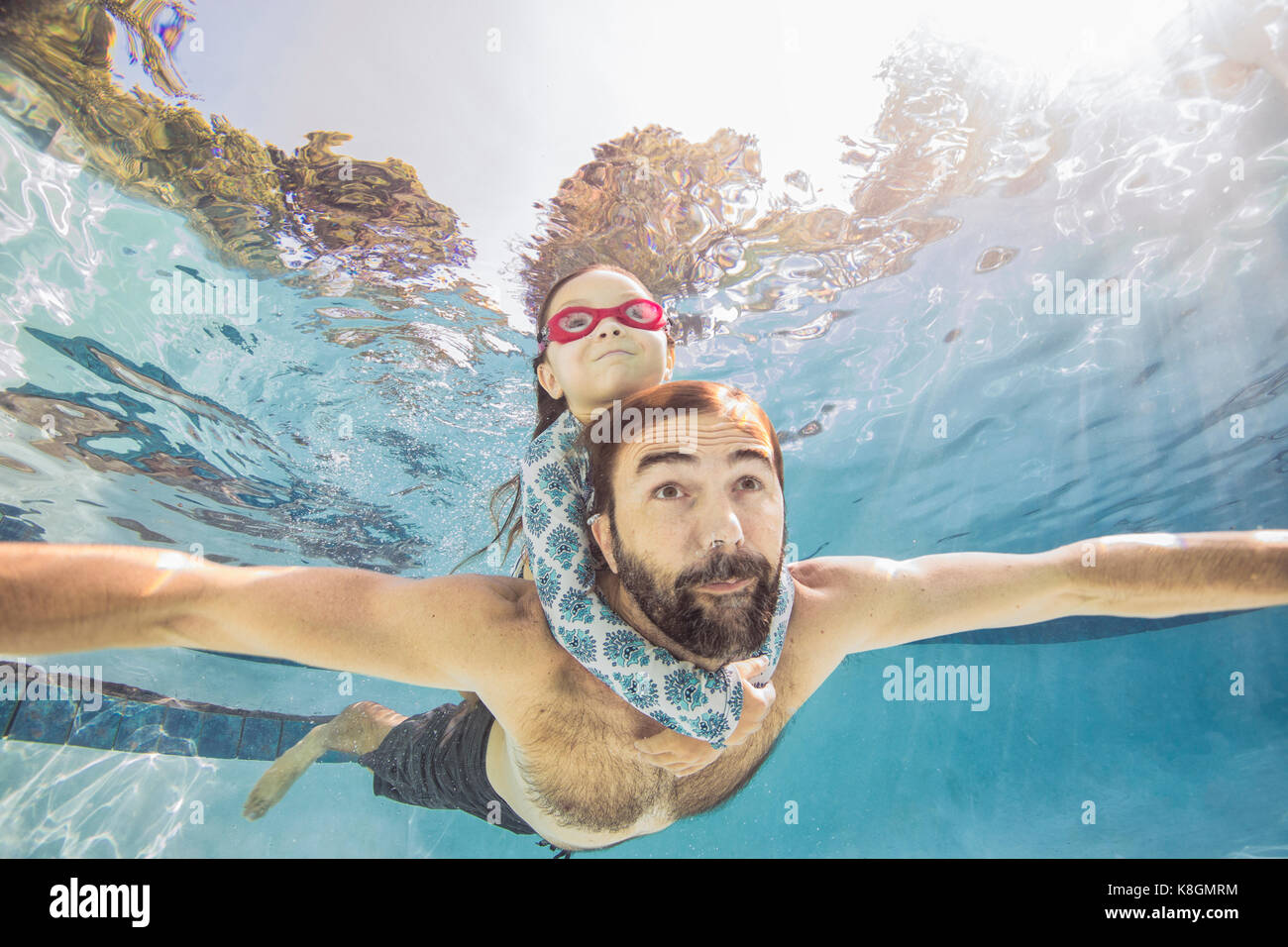 Vista subacquea di uomo maturo di nuoto con la figlia su piggy back Foto Stock
