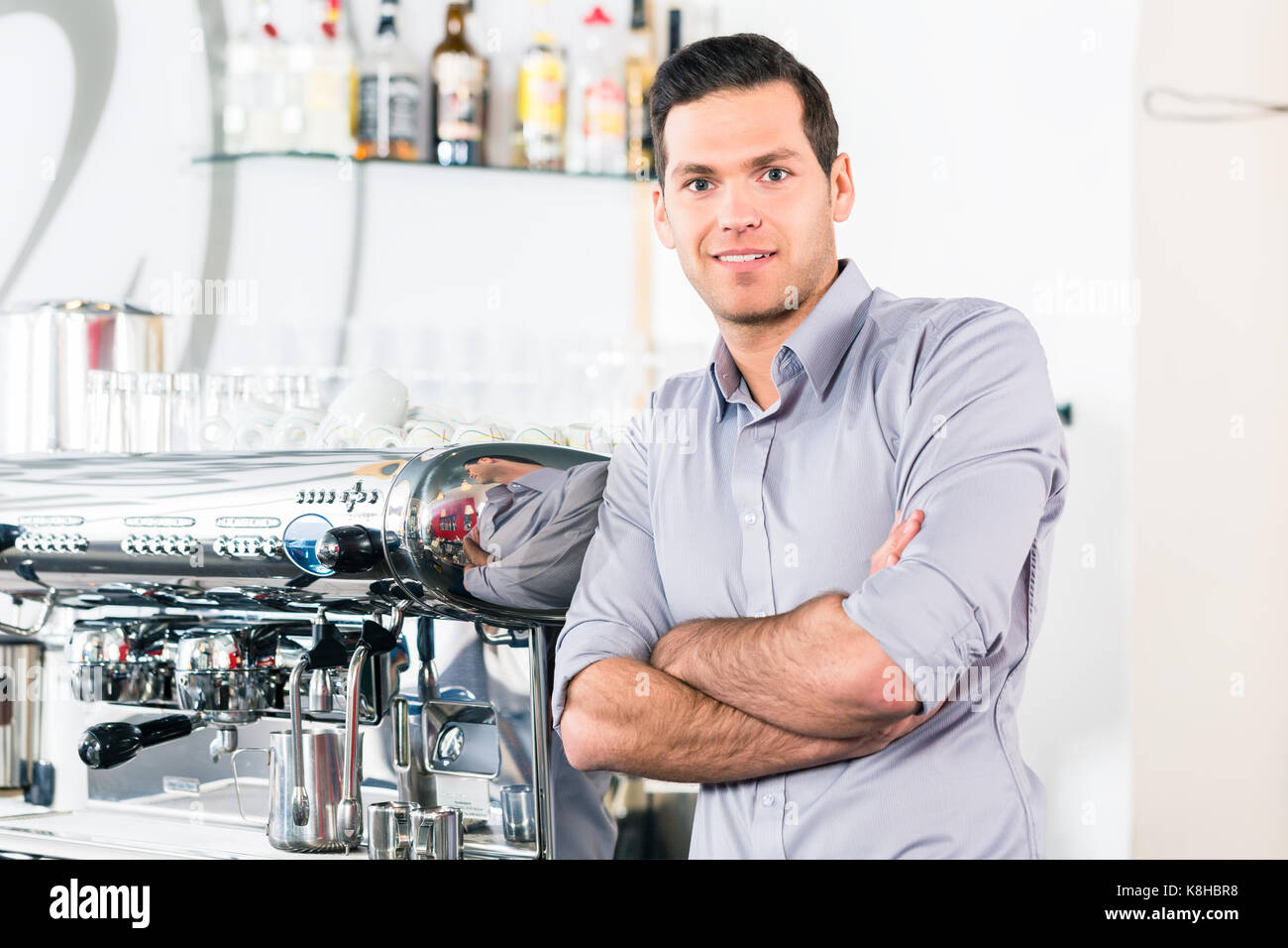 Giovane uomo che pongono nei pressi di un moderno automatico macchina da caffè Foto Stock