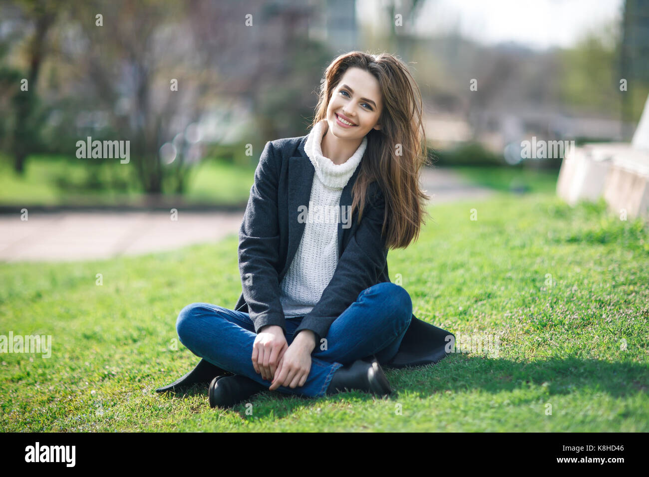 Bella donna sorridente seduto su un'erba all'esterno. Rilassatevi concept Foto Stock