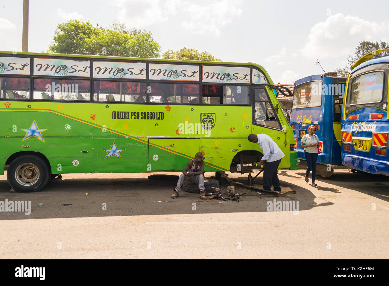 Due uomini bus di fissaggio ruota e assale da strada, Nairobi, Kenia Foto Stock