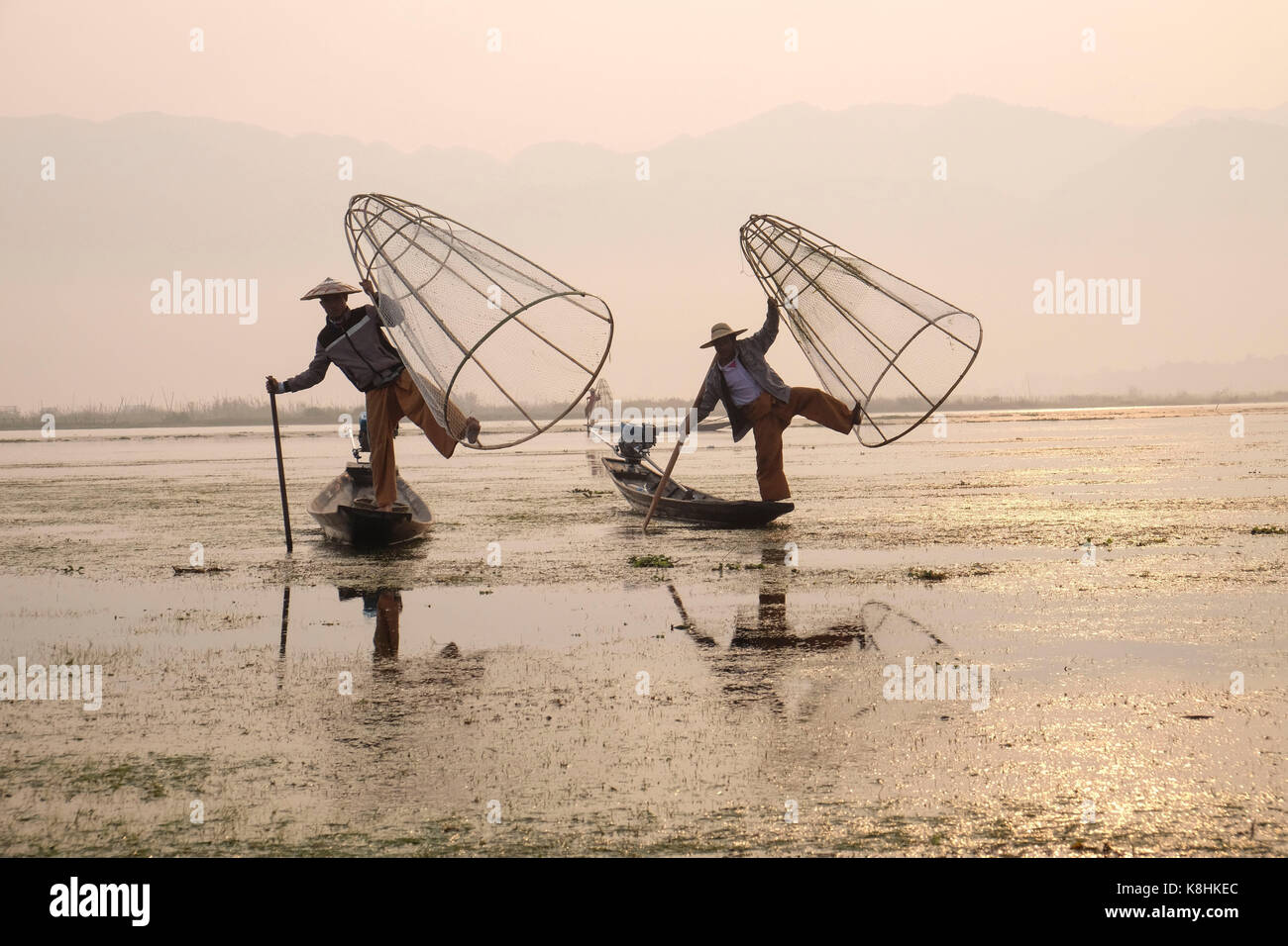 La birmania, myanmar: due pescatori su chiatte sul Lago Inle. I pescatori e a forma di cono trappola di pesce Foto Stock