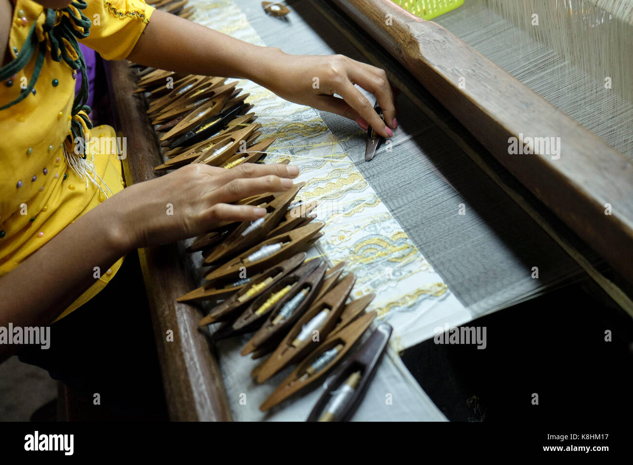 La Birmania, Myanmar Mandalay: laboratorio di tessitura. Le donne che lavorano nella parte anteriore di un telaio di tessitura: mani navette di movimentazione dei telai di tessitura Foto Stock