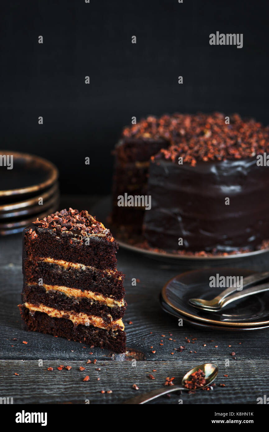 Pezzo di fatti in casa torta al cioccolato con crema al caramello sul tavolo irregolare Foto Stock