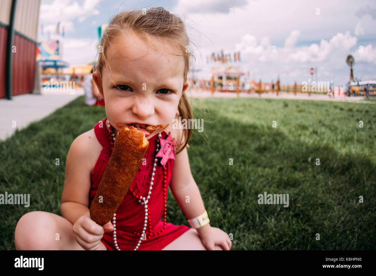 Ritratto di ragazza mangiare seduti sul campo erboso a park Foto Stock