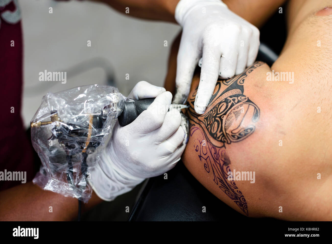 Mani tagliate di tattoo artist tatuaggio al cliente della spalla Foto Stock