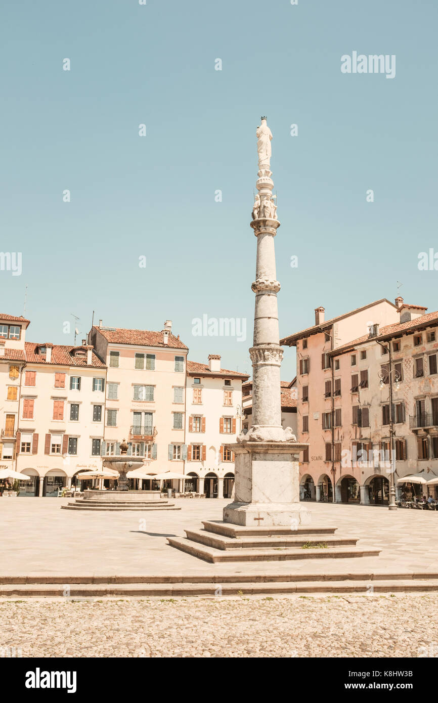 Statua sulla colonna architettonica contro edifici e cielo chiaro durante la giornata di sole Foto Stock