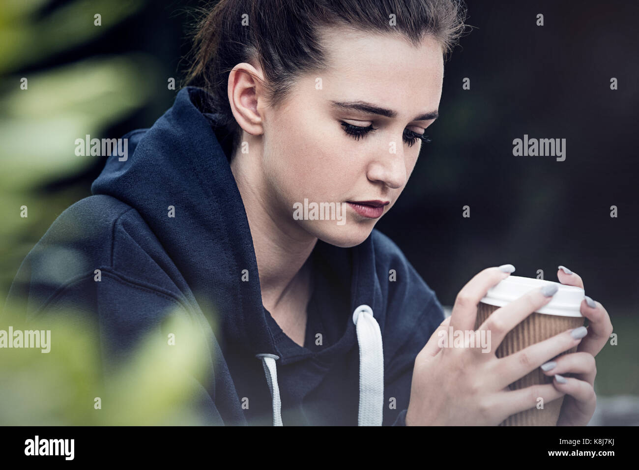 Bella triste premuto ragazza adolescente femmina giovane donna a bere il caffè da asporto al di fuori Foto Stock