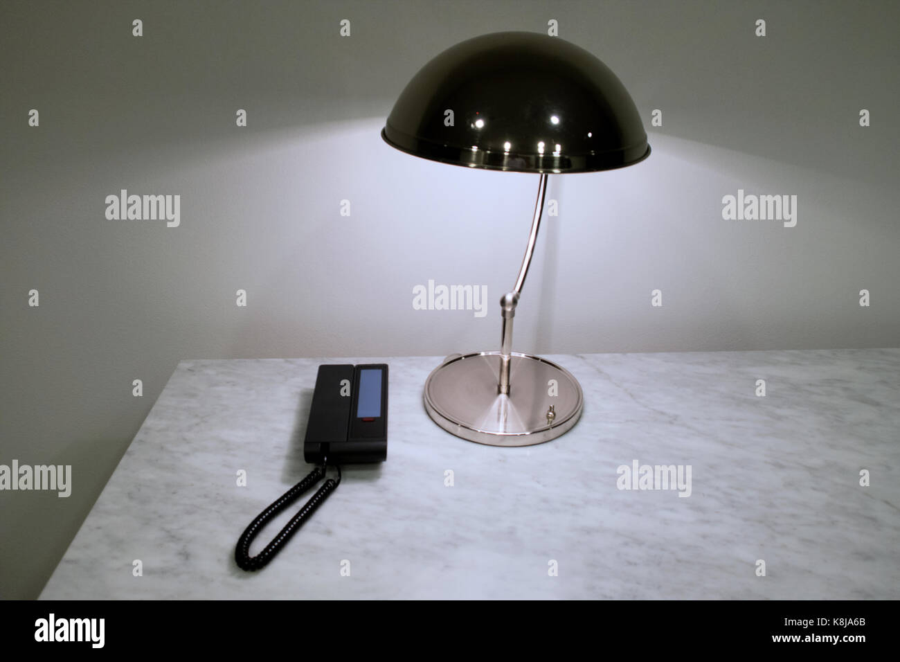 Un hotel di cortesia telefono su un tavolo con una lampada. Foto Stock