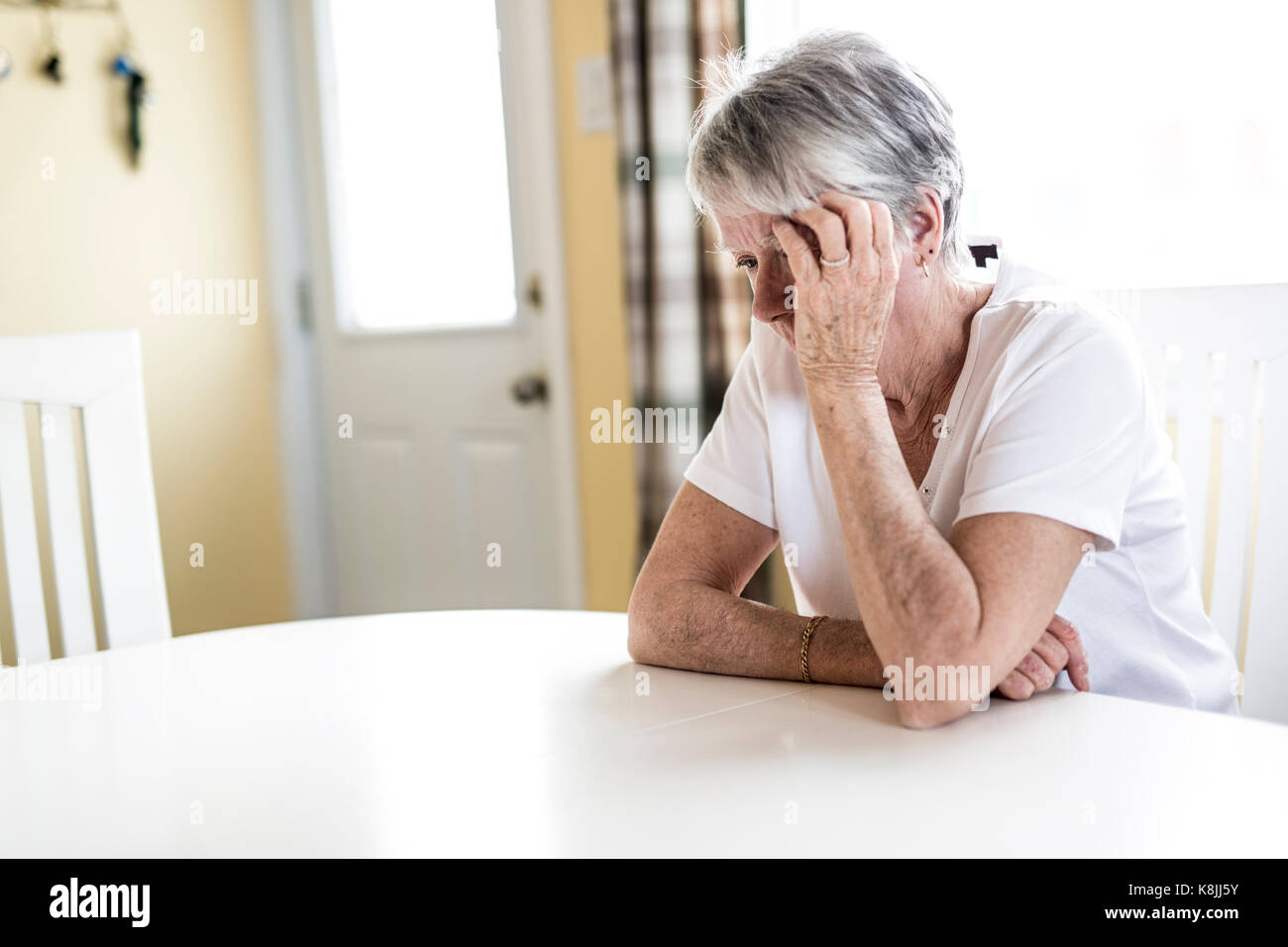 Donna matura a casa toccando la testa con le mani mentre con un mal di testa dolore Foto Stock