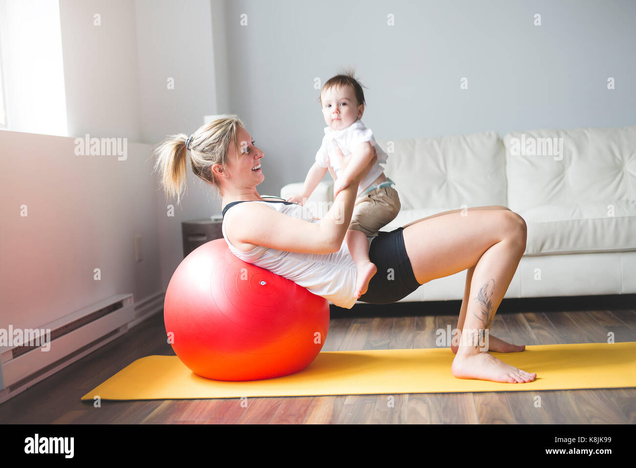 Sport madre è impegnata nel fitness e yoga con un bambino a casa Foto Stock