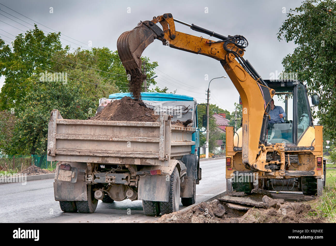Escavatore cingolato sulla strada asfaltata la riparazione Foto Stock