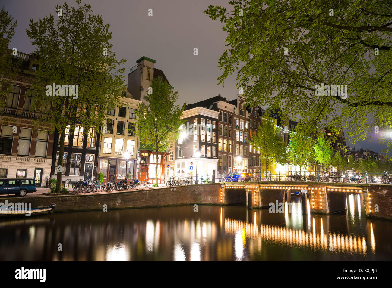 Vista notturna di Amterdam cityscape con canal, il ponte e le case medioevali nel crepuscolo della sera illuminata. Amsterdam, Paesi Bassi Foto Stock