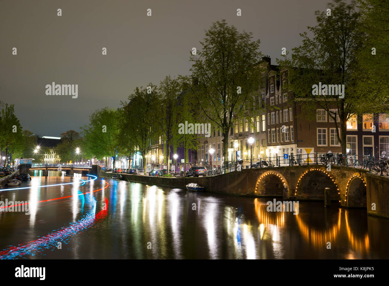 Vista notturna di Amterdam cityscape con canal, il ponte e le case medioevali nel crepuscolo della sera illuminata. Amsterdam, Paesi Bassi Foto Stock