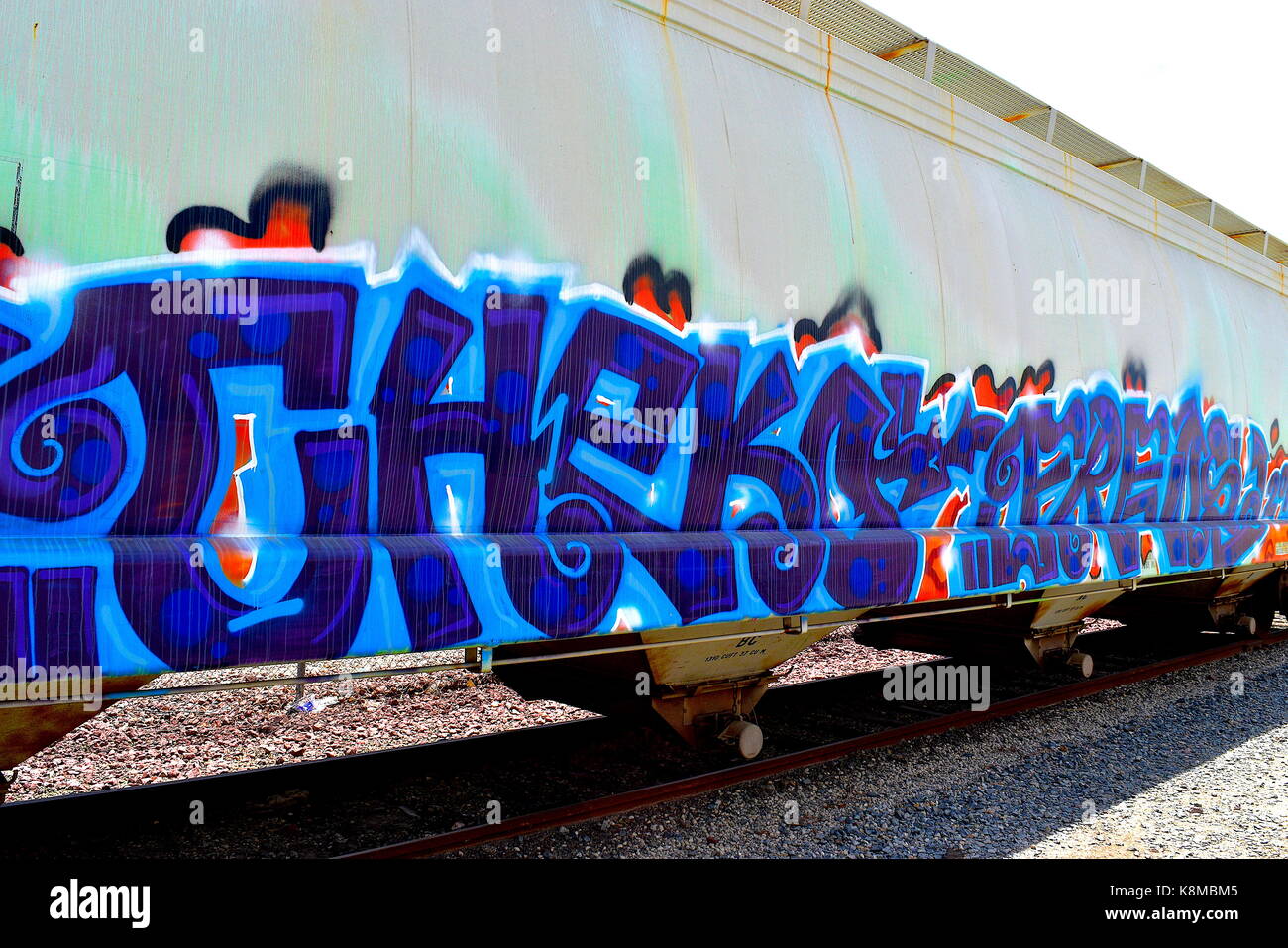 Colore orizzontale colpo di ferrovia parcheggiata contenitore con più strati di graffiti sul lato Foto Stock