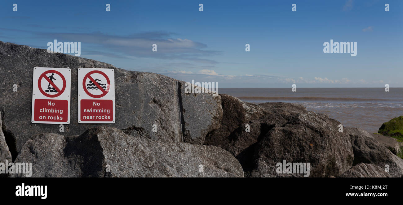 Cartelli di avvertimento fissato alla roccia mare difese a Southwold Beach, Suffolk, Inghilterra Foto Stock