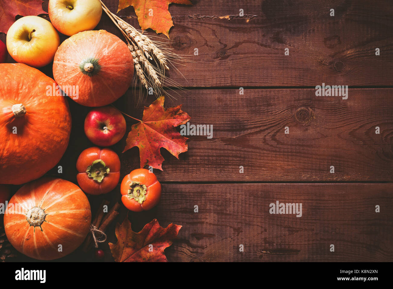 Sfondo del ringraziamento: zucche, mele, frumento, foglie di acero, coni e spezie in legno marrone. sfondo caduta stagionale sfondo per il giorno del ringraziamento Foto Stock