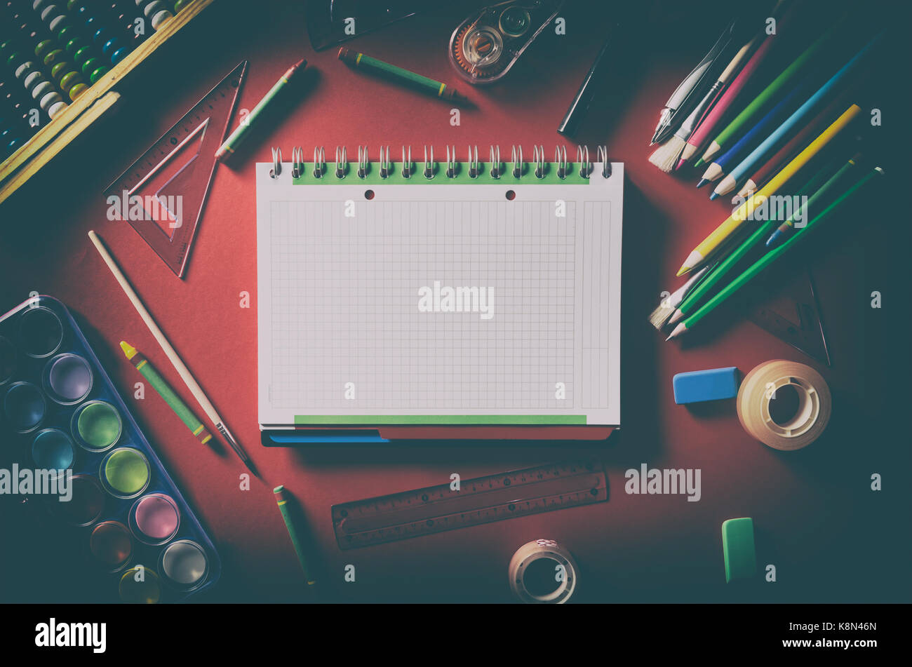 Blank notepad con forniture scolastiche, articoli di cancelleria, sfondo rosso. stationery office desk top visualizza tabella Studente della scuola ombra oscura nozione Foto Stock