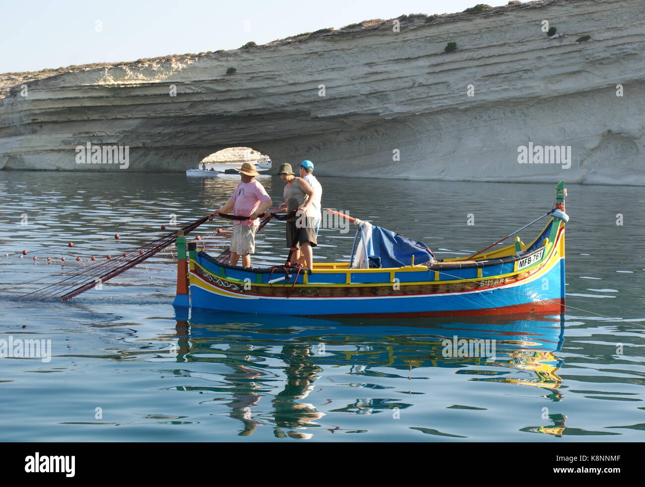 La pesca da un tradizionale colorato luzzu barca, Il-Hofra I-Kbira Bay, Malta Foto Stock