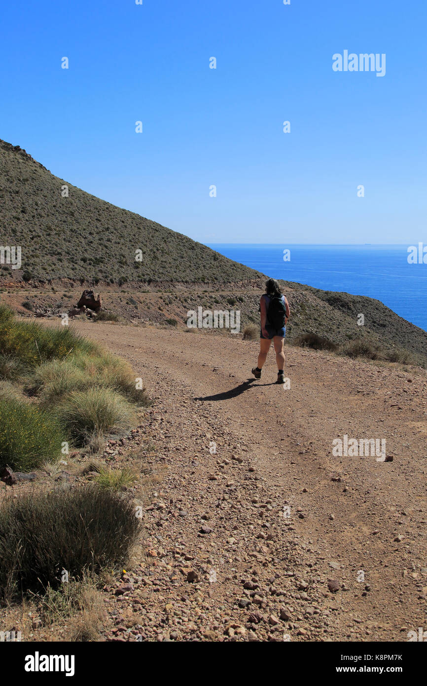 Donna camminando lungo il sentiero costiero nel Parco Nazionale Cabo de Gata, nei pressi di San José, Almeria, Spagna Foto Stock