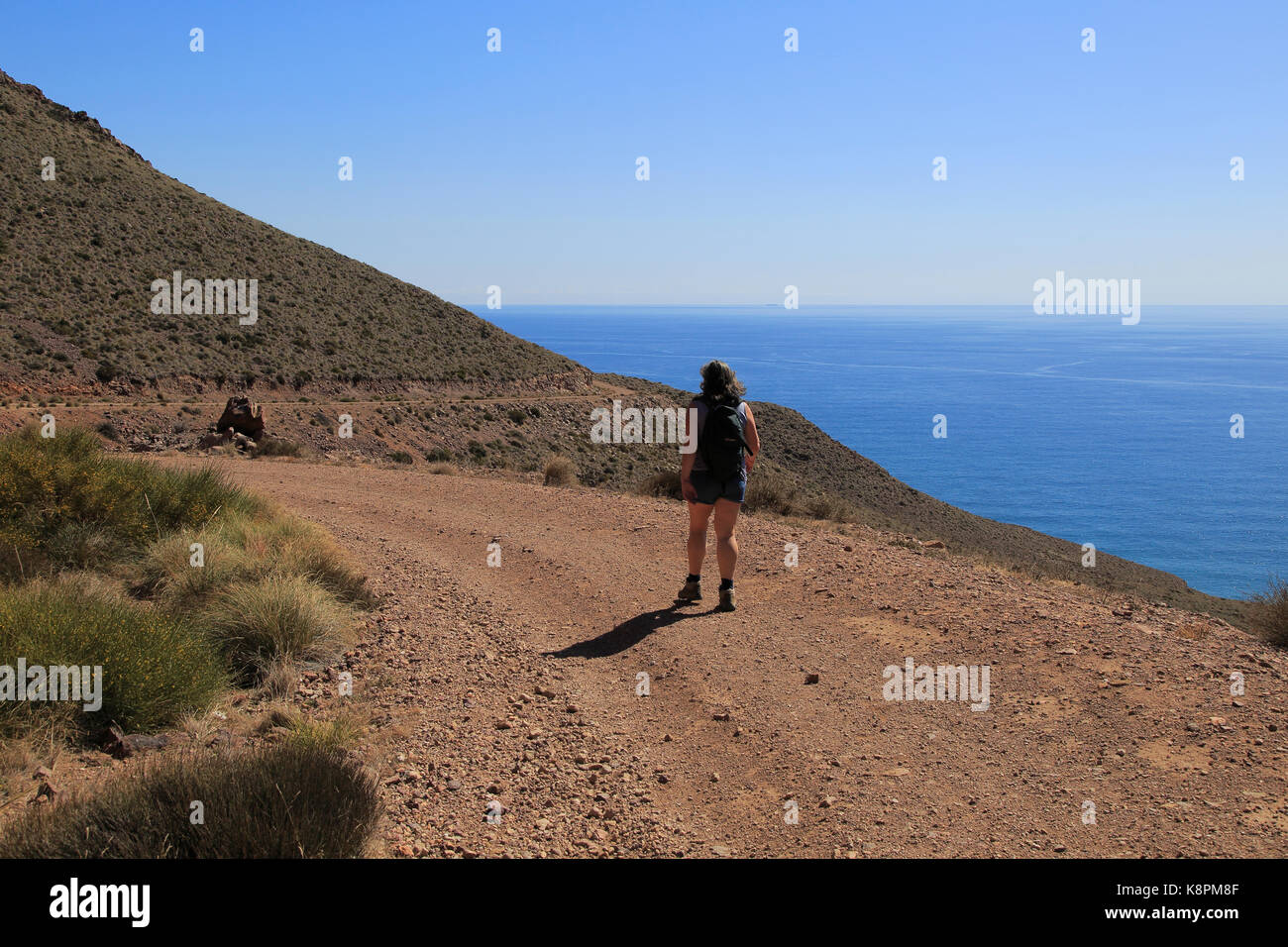 Donna camminando lungo il sentiero costiero nel Parco Nazionale Cabo de Gata, nei pressi di San José, Almeria, Spagna Foto Stock