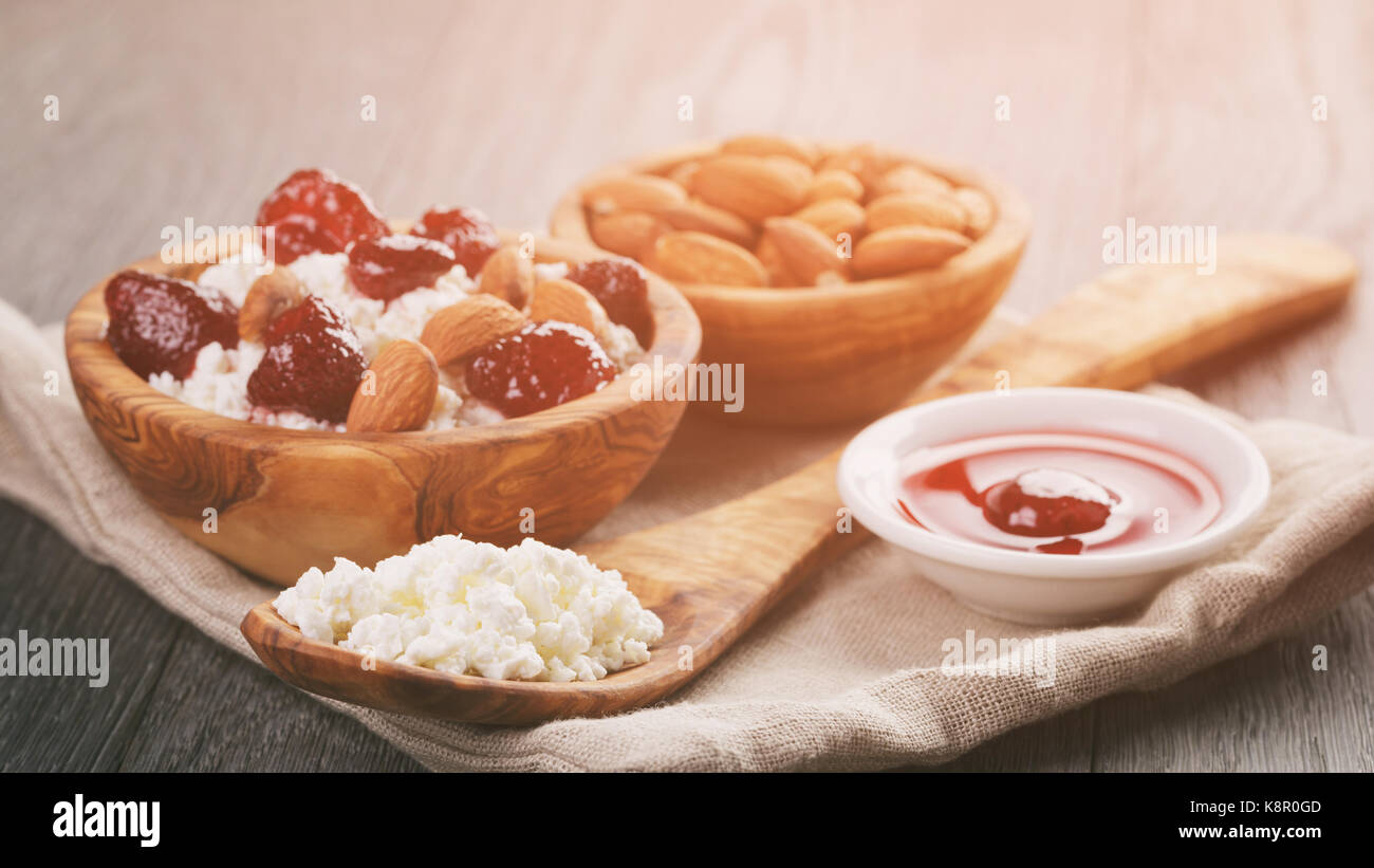 Formaggio con conserva di fragola in ciotola di legno su tavola in legno di quercia Foto Stock