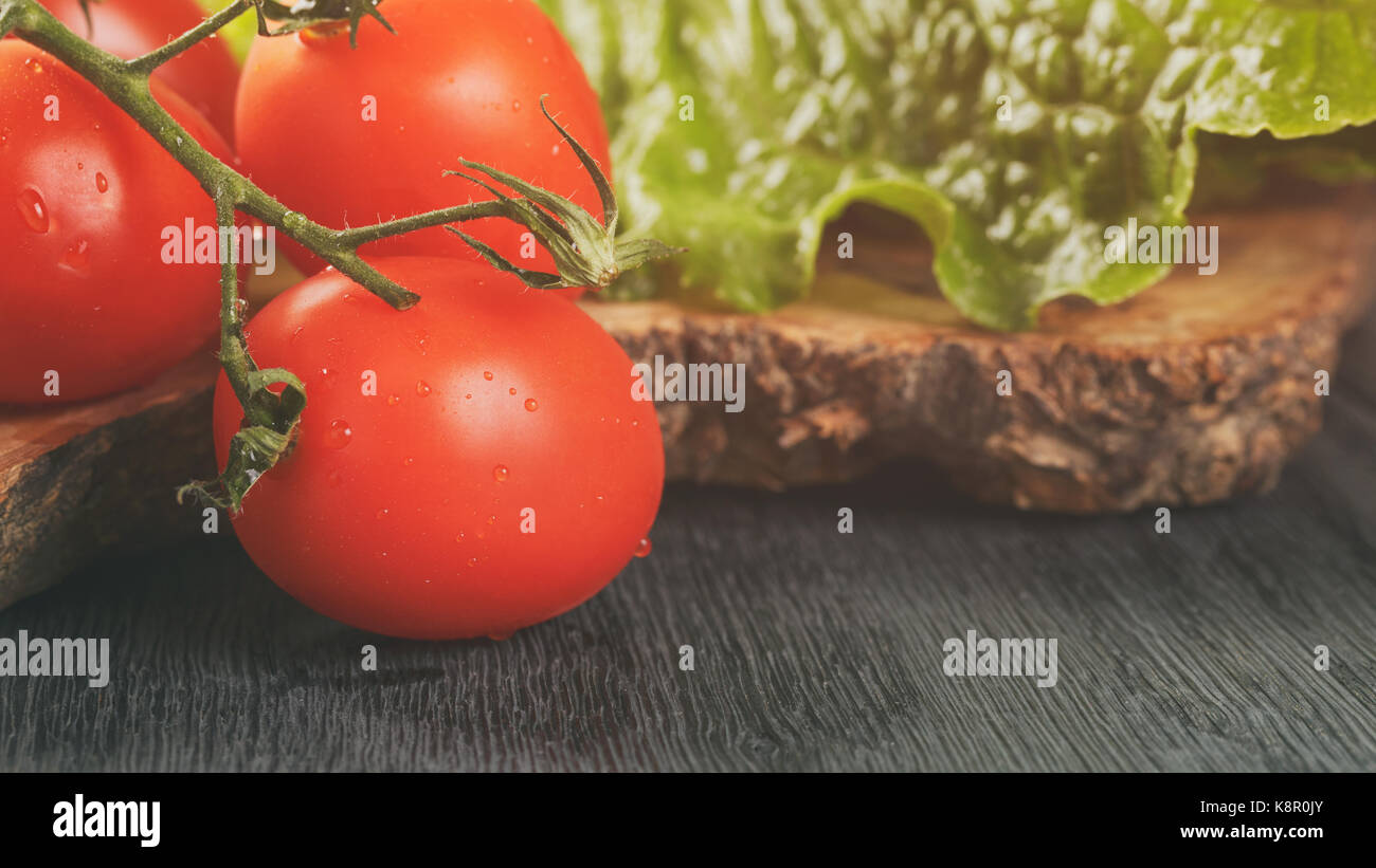 Romain fresca insalata verde e pomodori sulla scheda di oliva Foto Stock