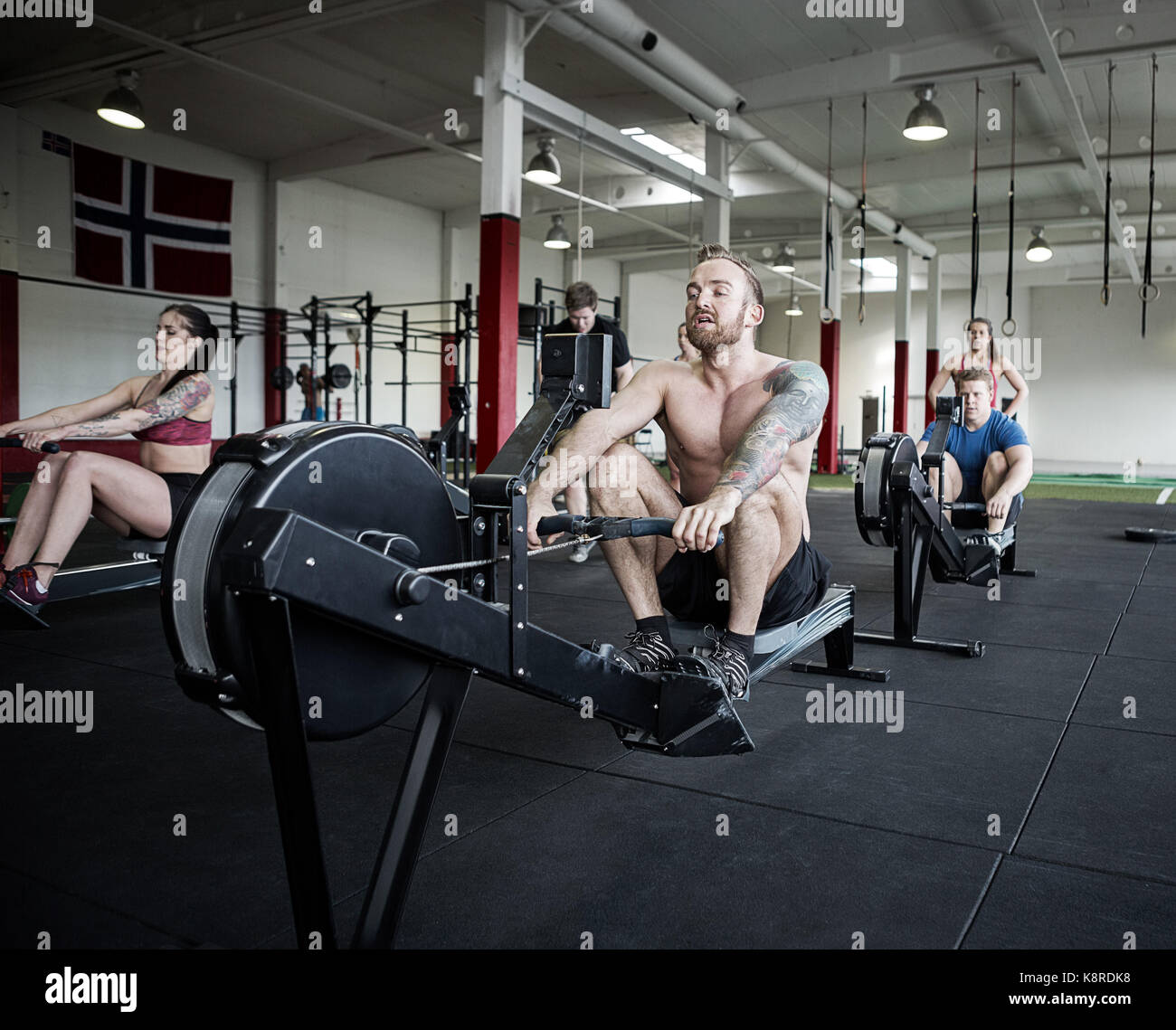 Gli uomini e le donne che usano i vogatori in palestra Foto Stock