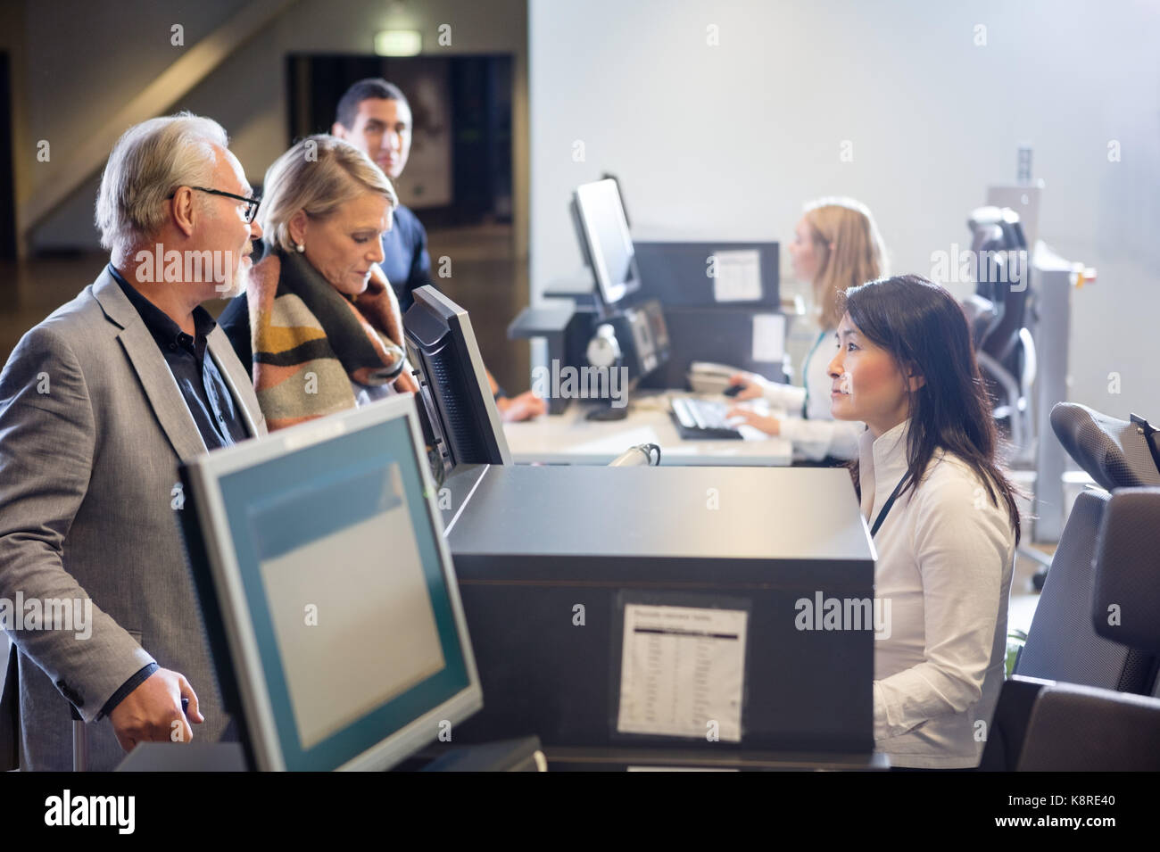 Il personale guardando senior business giovane al check-in in aeroporto Foto Stock