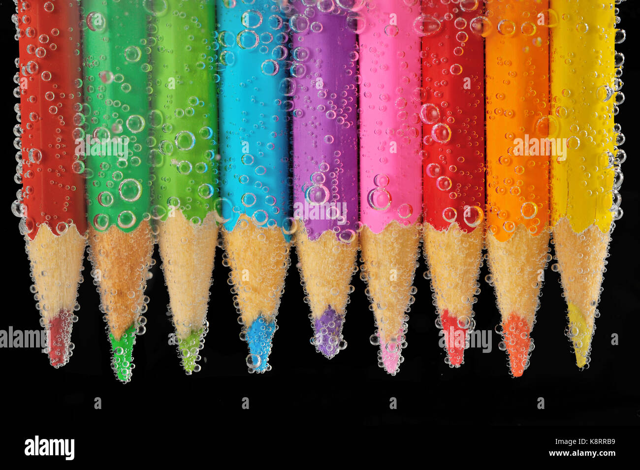 Matite di colore isolato su sfondo nero in acqua con bolle. close up Foto Stock