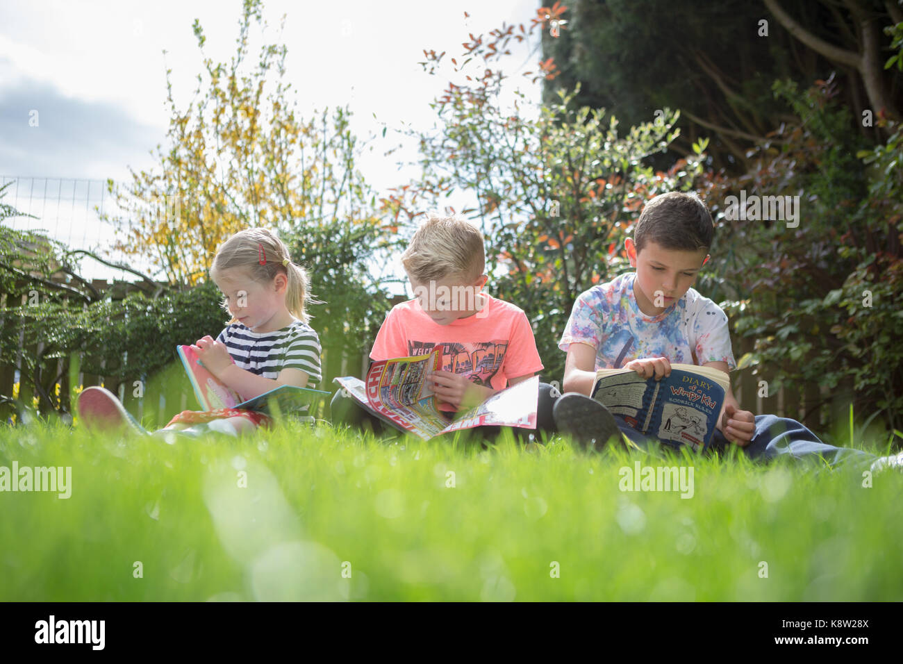 Lettura per bambini in giardino Foto Stock