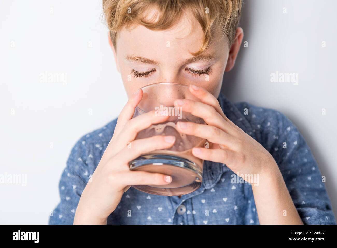 Sorridenti bambino bere il latte al cioccolato isolato su bianco Foto Stock