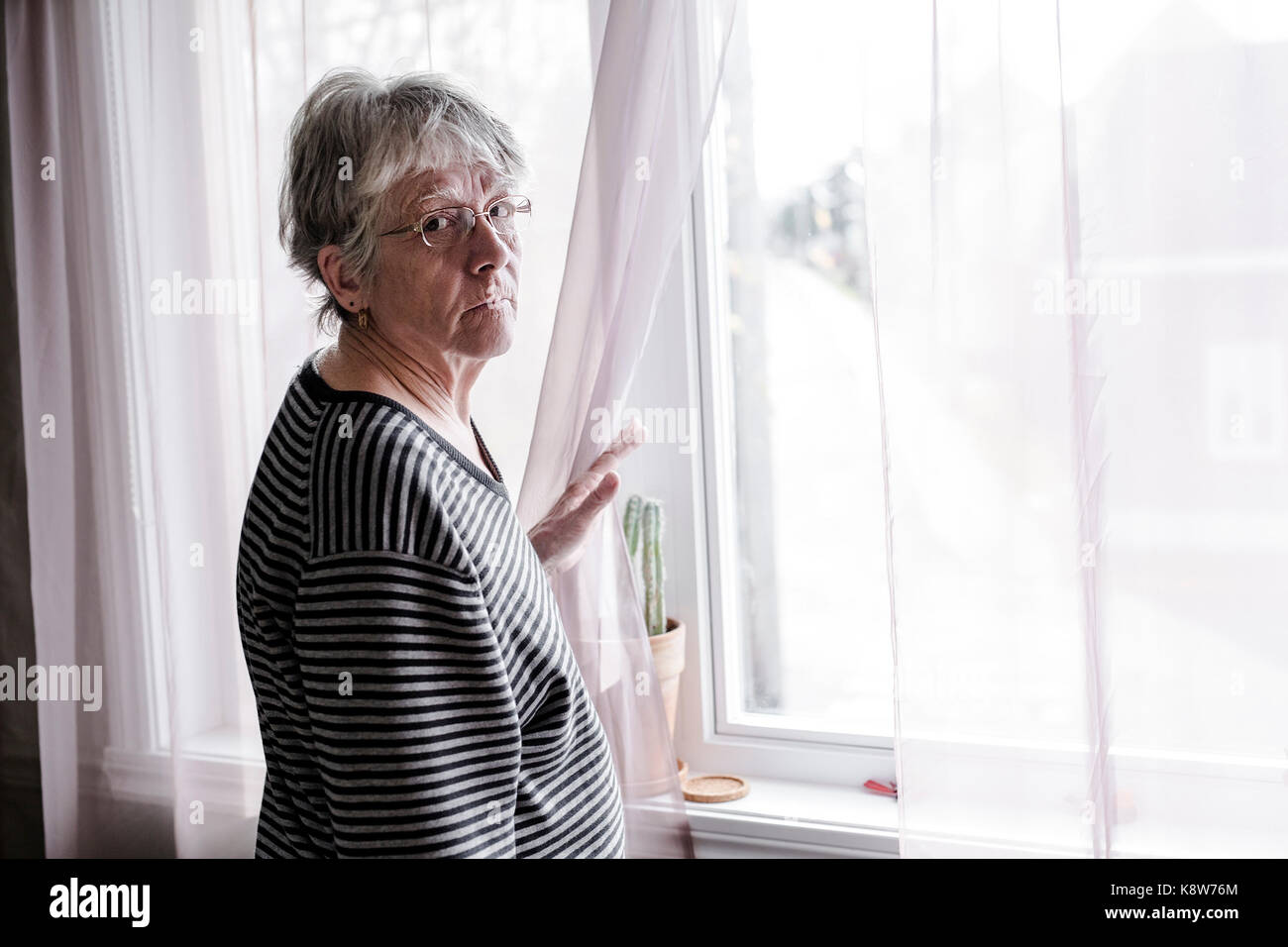 Preoccupato senior donna a casa il taglio molto male Foto Stock