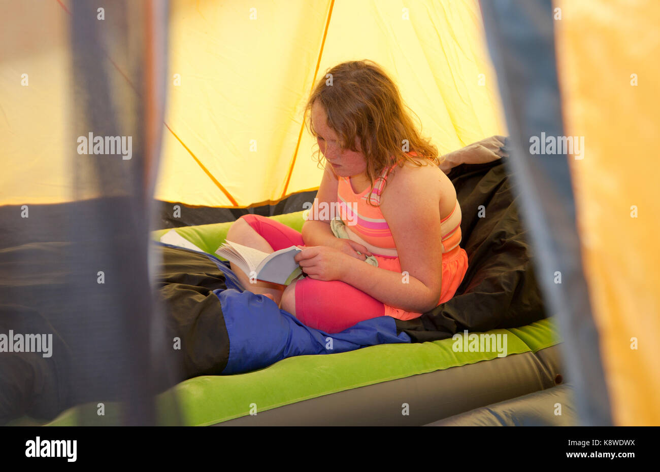 Bambina lettura dentro la sua tenda, incorniciato da tenda Foto Stock