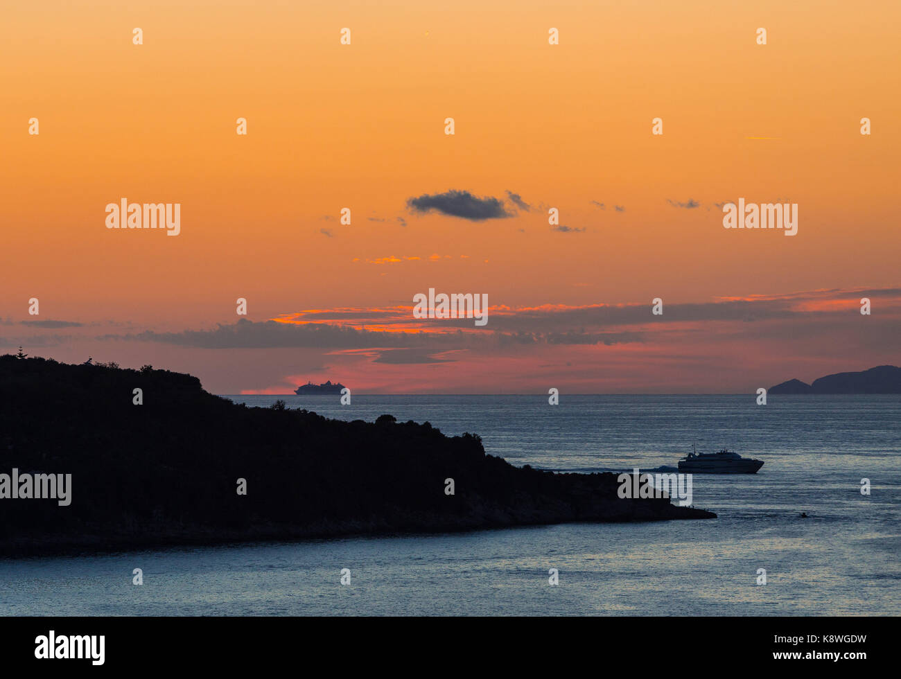 Sorrento, Italia, 18 settembre 2017. una nave da crociera scompare oltre l'orizzonte dopo il tramonto come un traghetto fa il suo modo per il porto di sorrento, Italia Foto Stock