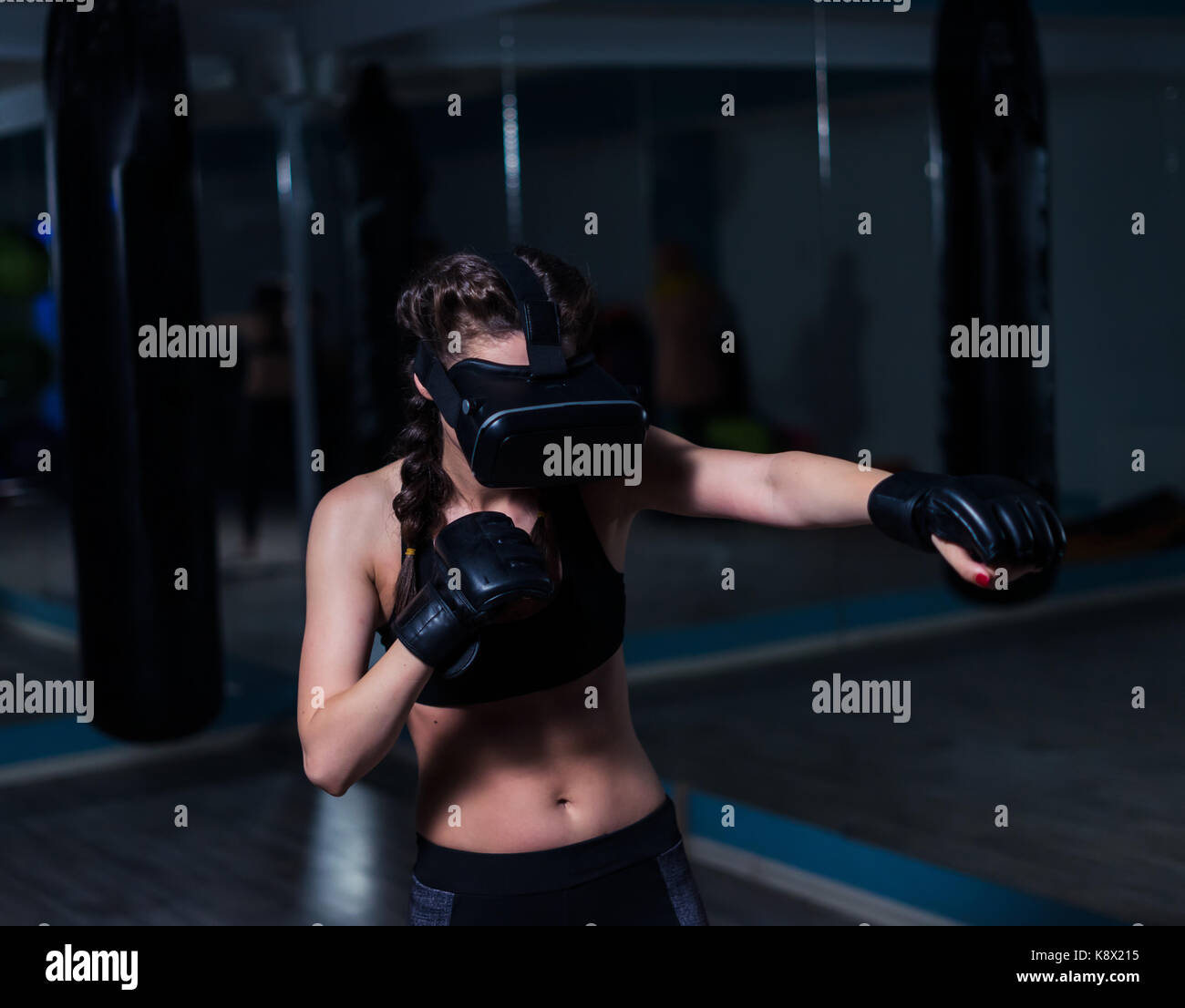 Giovani fighter boxer montare la ragazza di occhiali vr indossando guanti da boxe in formazione. gioco di boxe in realtà virtuale di 360 gradi. gioco futuristico Foto Stock