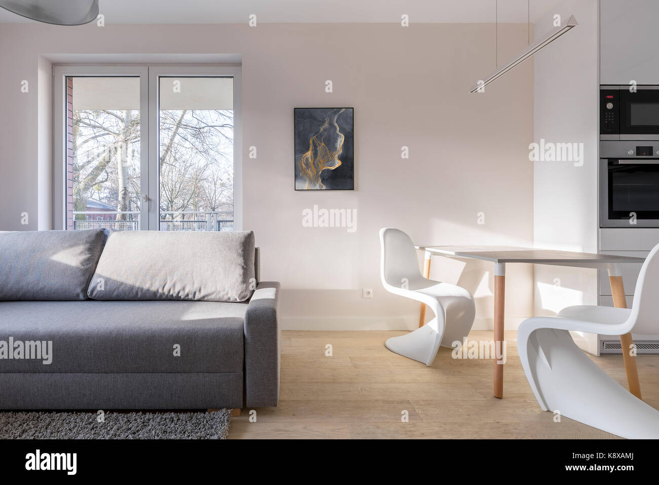 Home interno grigio con lettino, nuovo design sedie bianche e tabella semplice Foto Stock