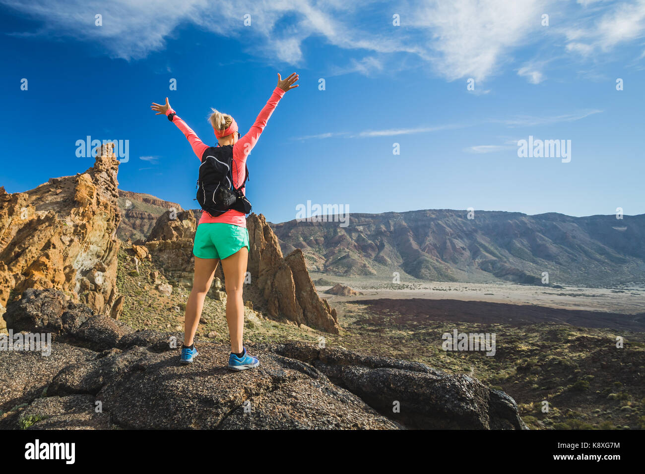 Escursioni o scalate successo con le braccia sollevate concetto. Guida femmina o escursionista celebrare sulla cima della montagna nel paesaggio di ispirazione sul sentiero roccioso piede Foto Stock