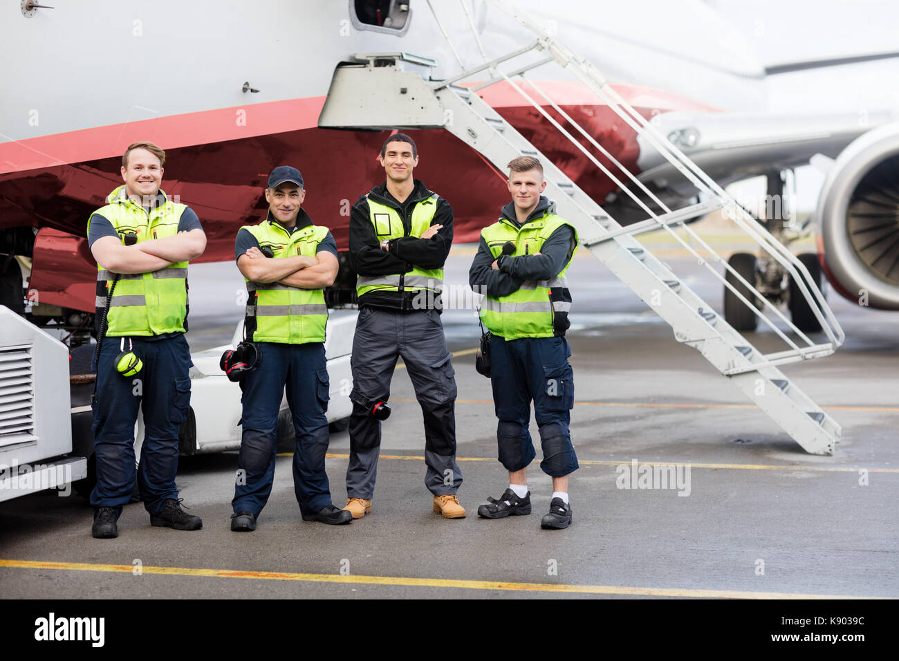 Ritratto di team di massa in piedi con le braccia incrociate contro aereo Foto Stock